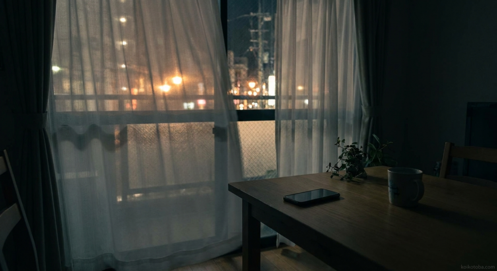 夜の窓際に伏せて置かれたスマートフォン